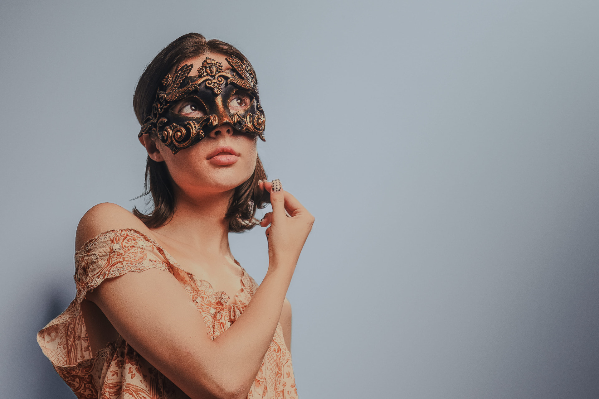 Editorial portrait of a model wearing an ornate Venetian mask